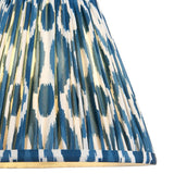 Close-up of Endon Brenwell 25cm tapered lamp shade in marlin blue, showing pleated faux silk with blue and white ikat pattern and taped edge trim.
