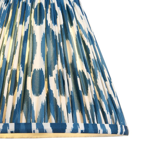 Close-up of Endon Brenwell 25cm tapered lamp shade in marlin blue, showing pleated faux silk with blue and white ikat pattern and taped edge trim.