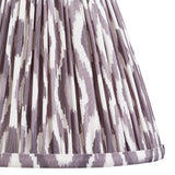Close-up of Endon Brenwell 25cm tapered lamp shade in pearl grey, showing pleated faux silk with ikat pattern in grey and white and taped lower edge.