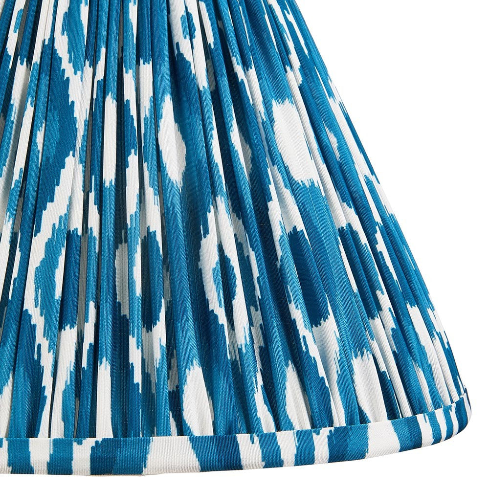 Close-up of Endon Brenwell 30cm tapered lamp shade in marlin blue, showing pleated faux silk with a blue and white ikat print and taped edge.