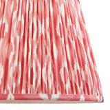 Close-up of Endon Brenwell 35cm tapered lamp shade in coral pink and white ikat print on pleated faux silk with taped edge detailing.