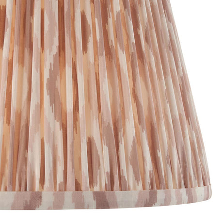 Close-up of Endon Brenwell 35cm tapered lamp shade in neutral, showing pleated faux silk with a soft pink and cream ikat print and taped edge trim.