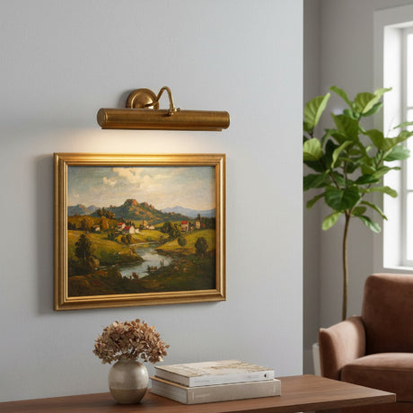Brimora Brass Picture Light, 35.5cm tubular hood on a swan-neck arm, mounted above a gilt-framed landscape painting on a grey living room wall.