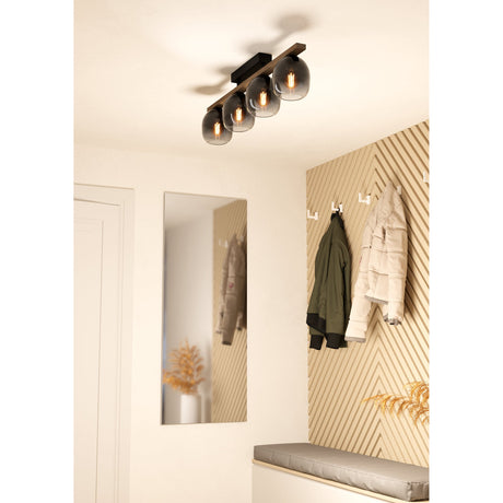Brinvelle 4 Light Ceiling Light featuring a black steel canopy and brown wood bar with four smoked glass shades, mounted above a hallway with mirror and coat hooks.