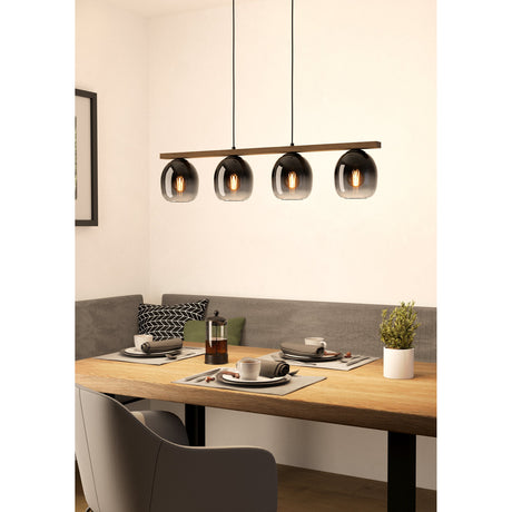 Brinvelle Smoked Glass Linear Pendant Light with four rounded smoked glass shades on a brown wooden bar, black cords and canopy, shown above a dining table.