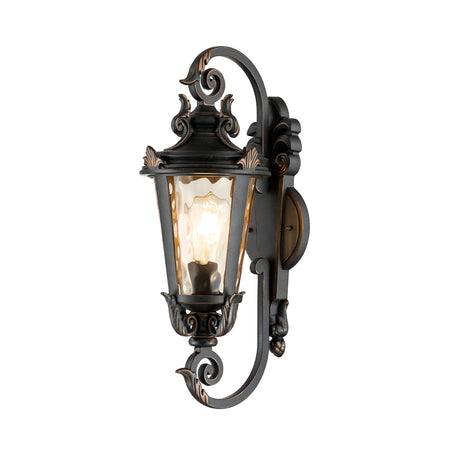The Baltimore 1 Light Outdoor Medium Wall Lantern in weathered bronze showcases a vintage-style design with detailed scrollwork. Its clear glass panels allow the glowing bulb to embody a classic vintage-inspired aesthetic.