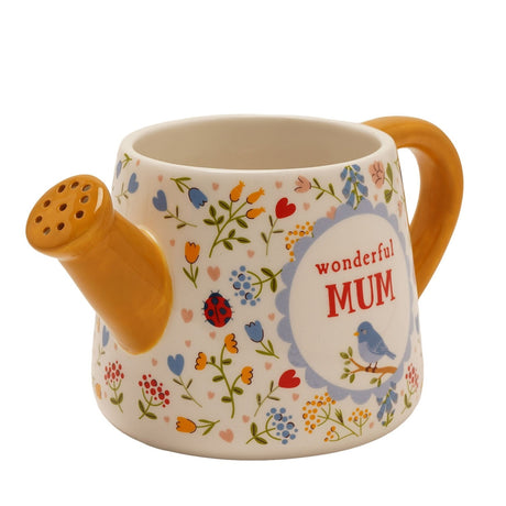 Stoneware mug shaped like a watering can with yellow spout and handle, cream floral body, blue bird medallion reading "wonderful MUM" in red, on a white background.