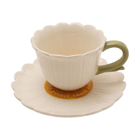 Daisy Gloss Stoneware Teacup and Saucer Set in white, with fluted petal-shaped cup, green handle, and daisy-form saucer featuring a yellow centre, on a plain white background.