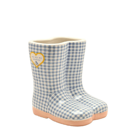 Ceramic planter shaped like wellington boots in blue and white gingham with peach soles, cream rim, and a yellow heart reading you are my sunshine, on a white background.