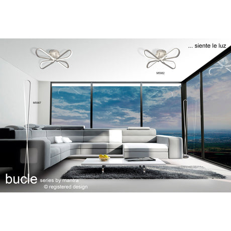 Modern living room with large windows and minimalist white furniture, featuring the Bucle Dimmable LED Floor Lamp 50W 3000K in Silver & Chrome. Text reads: bucle series by mantra and ...siente le luz.