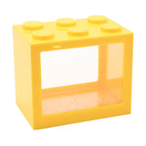 Yellow plastic money box shaped like a building block with six round studs on top and a clear front window showing the storage area, shown on a plain white background.
