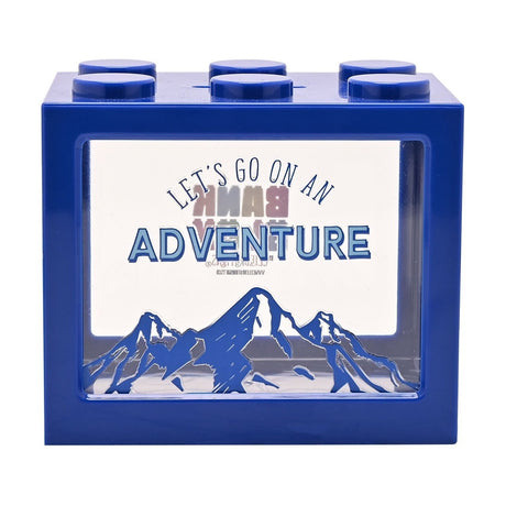 Navy blue plastic block-shaped money box with six round top studs and coin slot, clear front window printed with "Let's Go on an Adventure" above jagged mountain peaks, on a plain white background.