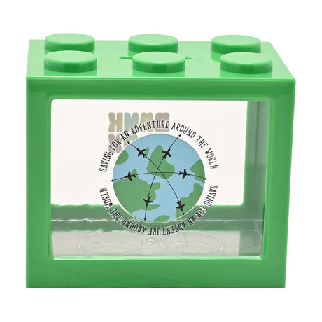 Green plastic building block-shaped money box with six top studs, a coin slot, and a clear front panel printed with a globe, aeroplane paths, and "Saving for an adventure around the world".