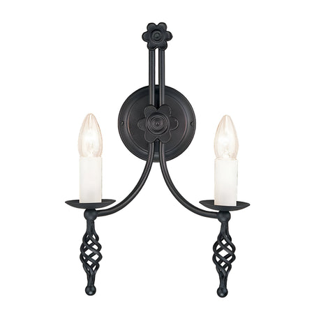 The Belfry 2 Light Wall Light in black highlights medieval craftsmanship with its wrought-iron construction, featuring hand-forged floral and geometric elements. It includes two candle-shaped light bulbs designed to mimic traditional candles, providing a symmetrical design that infuses any room with timeless elegance.