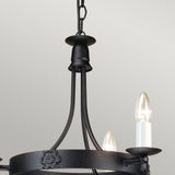 Close-up of the Belfry 3 Light Chandelier - Black highlighting its medieval craftsmanship. This chandelier, constructed from black wrought iron with a hand-forged metal frame and decorative floral accents, features two candle-shaped bulbs set against a light gray background.