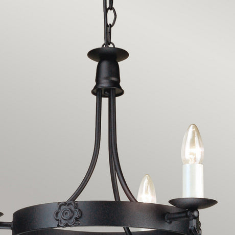 Close-up of the Belfry 3 Light Chandelier - Black highlighting its medieval craftsmanship. This chandelier, constructed from black wrought iron with a hand-forged metal frame and decorative floral accents, features two candle-shaped bulbs set against a light gray background.