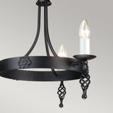 The Belfry 3 Light Chandelier - Black highlights stunning medieval artistry with a hand-forged metal frame. This elegant black chandelier displays two candle-shaped light bulbs and intricate twisted metal designs featuring a floral motif, beautifully contrasted against a simple light gray background.