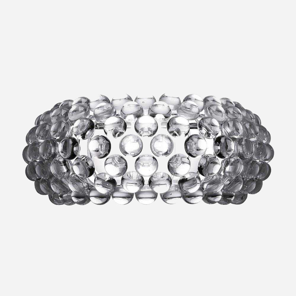 The Briller LED Large Wall Light - Transparent is displayed against a plain white background. Its transparent design forms a structured pattern, offering a shiny, textured appearance with a modern aesthetic.