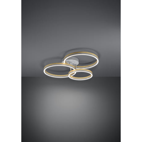 Cadinaro LED flush ceiling light with three overlapping grey rings edged in warm wood-brown tones, mounted close to the ceiling on a round grey canopy against a dark grey background.