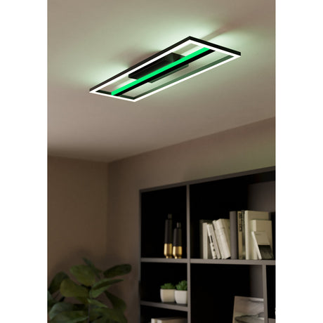 Calagrano Smart LED Flush Ceiling Light in black aluminium and steel, rectangular design with glowing outer frame and central green light bar, shown on a bedroom ceiling above a dark bookshelf.