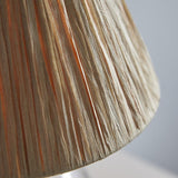 Close-up of the Caldwood 25cm tapered lamp shade in natural raffia, showing hand-wrapped woven texture in earthy brown tones against a light grey background.