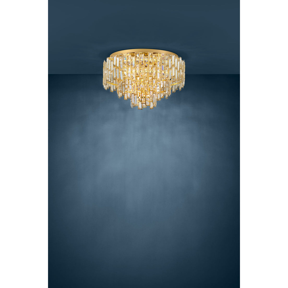 Calmeilles 10 Light Ceiling Light in brass, a round flush-mount fixture with tiered rows of faceted glass drops, shown against a dark blue background.