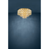 Calmeilles 10 Light Ceiling Light in brass, a round flush-mount fixture with tiered rows of faceted glass drops, shown against a dark blue background.