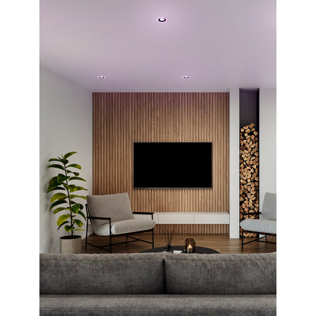 Calonge RGB LED Downlight Set of 3 in black and white recessed into a white ceiling, shown glowing purple above a living room with wood-panelled TV wall.
