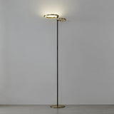Castelpoto 1 LED floor lamp with two brushed brass illuminated rings at varying heights atop a slim black steel stem and round brushed brass base, shown against a plain light background.
