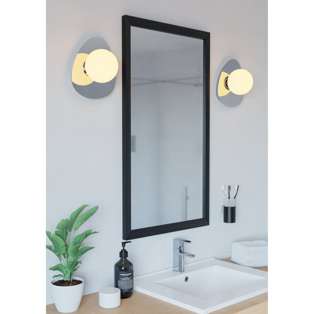 Castrovido bathroom wall lights in chrome with pebble-shaped backplates and opal glass globe shades, mounted either side of a black-framed mirror above a washbasin.