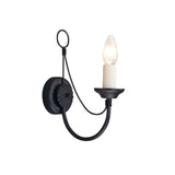 The Carisbrooke Wall Light - Black has a Gothic-inspired design with a loop handle and curved arm that holds a single candle-shaped white bulb. Its candelabra-style structure offers simplicity and elegance, making it ideal for ambient lighting with a vintage feel.