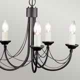 The Carisbrooke 5 Light Chandelier in black features candelabra-style arms, each adorned with a candle-shaped light bulb, set against a plain light gray background. Its simple yet elegant design offers a charming vintage appeal.