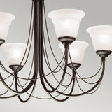 A close-up of the Carisbrooke 6 Light Chandelier - Black highlights its dark metal frame and multiple curved arms, each supporting a frosted white glass lampshade. The plain light gray backdrop enriches its vintage aesthetic with a touch of Gothic elegance.