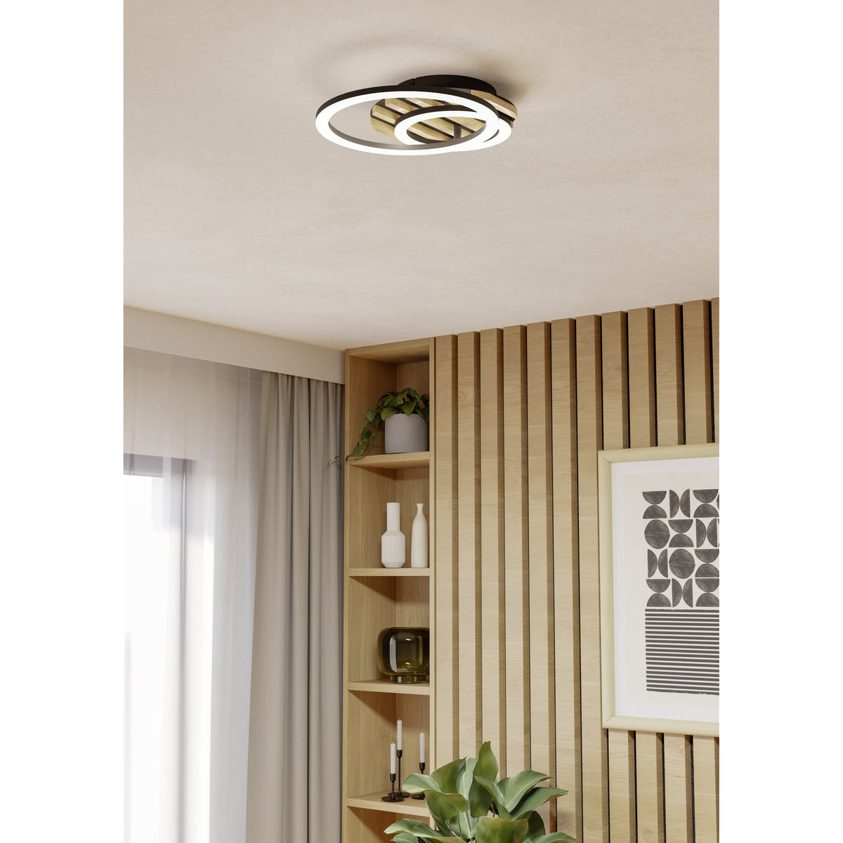Cembrano LED flush ceiling light in black and natural wood with two overlapping illuminated rings, mounted above a wood-panelled wall with shelving in a living space.