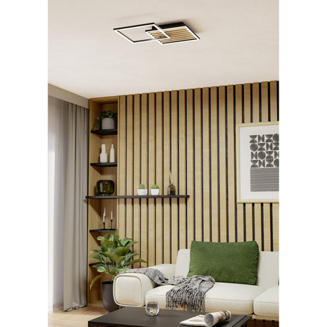 Cembrano LED flush ceiling light with two offset square black frames, one open and one lined with natural wooden slats, mounted on a living room ceiling above a wood-slatted wall.