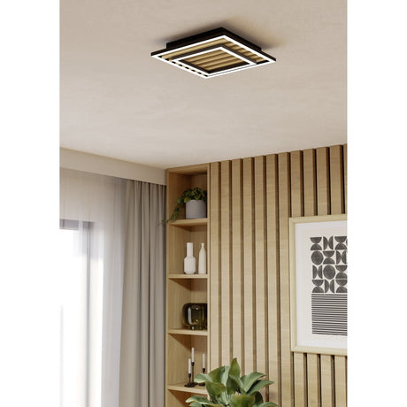 Cembrano LED flush ceiling light in black and natural, square stepped frame with wood slats, mounted on a textured ceiling in a living room with wood-slat wall and shelving.