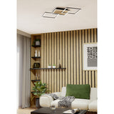 Cembrano LED flush ceiling light, 92.5cm, with overlapping black square frames and a natural wood slat panel, shown mounted on a living room ceiling above a wood-slatted feature wall.