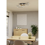 Cembrano LED Flush Ceiling Light 92.5cm in black with natural wood-slat panel, mounted on a dining room ceiling above a wooden table and light upholstered chairs.