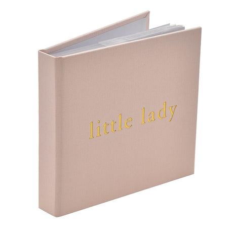 Square photo album with a soft pink woven linen cover, standing upright and slightly open to show white pages, with "little lady" embossed in gold lettering on the front.