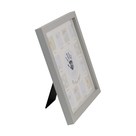 Grey MDF multi-aperture photo frame with "My First Year" cream mount, central handprint circle, and twelve monthly photo slots, shown at an angle on a plain white background.