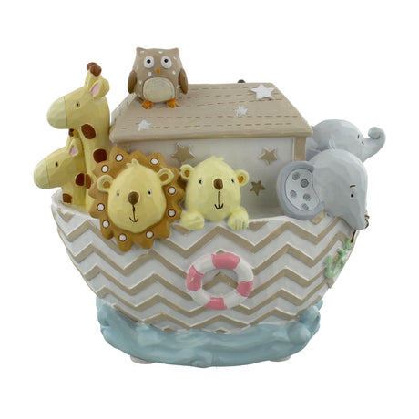 Hand painted resin money box shaped like Noah's Ark, with giraffes, a lion, bear, elephant and owl on a chevron-patterned hull, set on a plain white background.