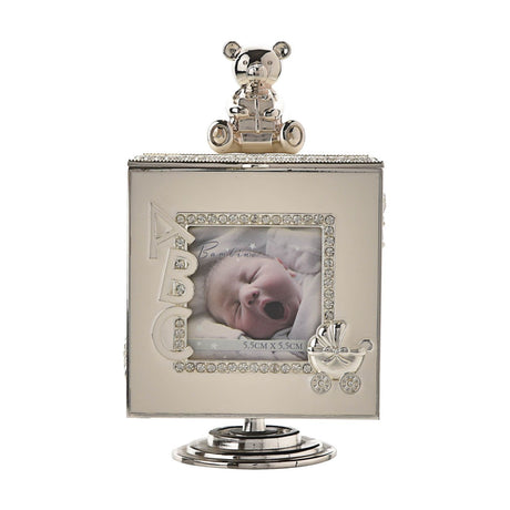 Square silverplated trinket box photo frame in ivory and silver with teddy bear on lid, crystal-edged opening showing ABC lettering and pram detail, on pedestal base.
