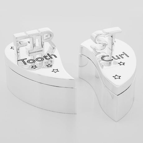 Split heart-shaped keepsake box in silverplated metal, dividing into two lidded sections engraved with raised "FIRST" lettering and "Tooth" and "Curl," shown on a plain white background.