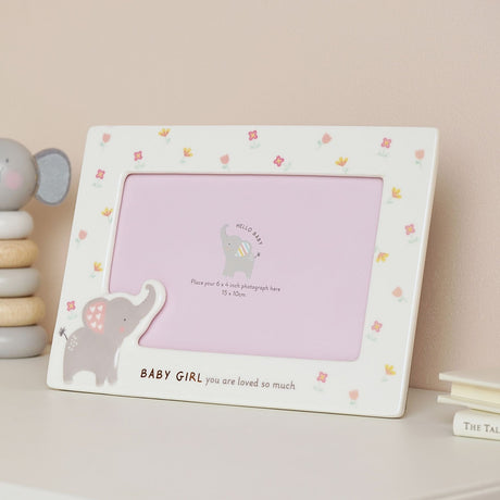 White ceramic photo frame with floral border and grey elephant detail, reading "Baby Girl you are loved so much," displayed on a shelf for a 6x4 inch photo.