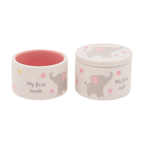 Round white ceramic keepsake box set with pink interiors, printed elephant, floral and heart details, reading "My first tooth" and "My first curl", on a plain background.