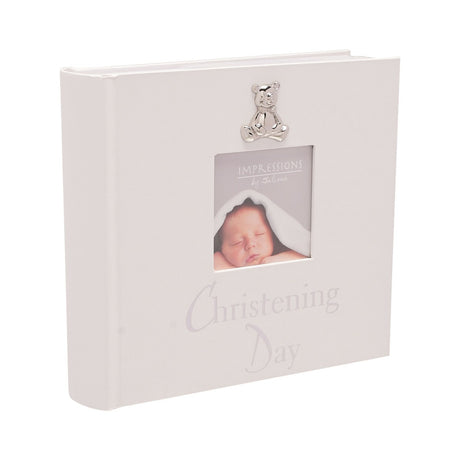 White pearlised Christening Day photo album with silver teddy bear charm and square photo window on the cover, for 6 x 4in prints, shown on a plain background.