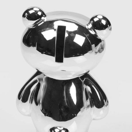 Silver plated teddy bear money box in close-up, showing round ears, coin slot on the head, and a glossy metal finish against a plain white background.