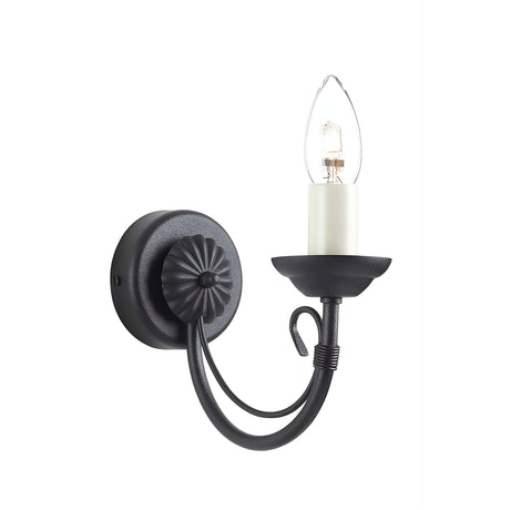 The Chartwell 1 Light Wall Light - Black boasts a timeless candelabra style with a curving arm and an exposed bulb that mimics the look of a candle. The round base is beautifully detailed with a decorative rosette pattern, enhancing its classic black finish.