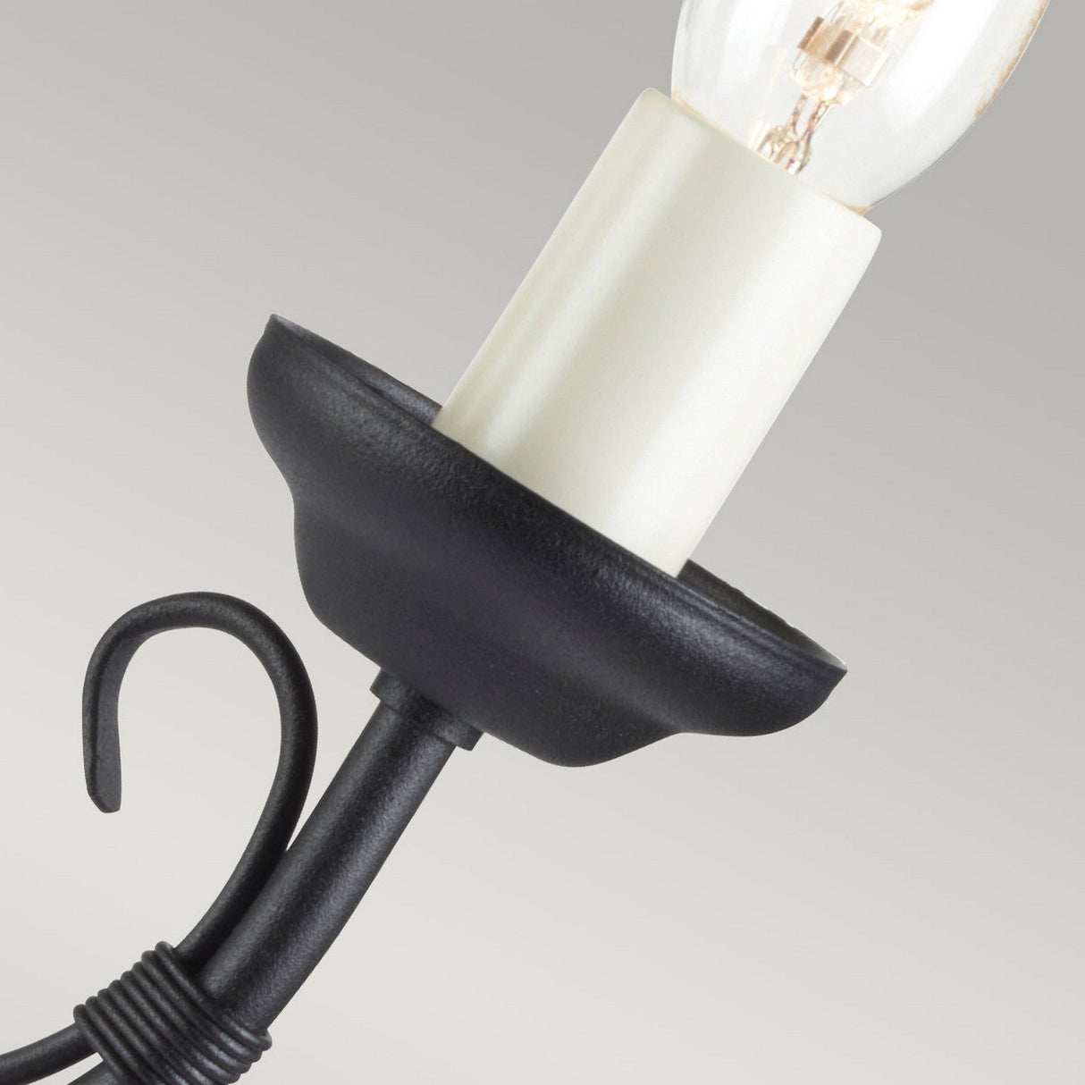 Close-up of a black hanging lantern with an exposed light bulb, exuding traditional charm. The lantern boasts a curved metal hook at the base and a smooth, light-colored socket cradling the bulb. This piece evokes the Chartwell 2 Light Wall Light - Black, bringing modern flair against a simple gradient backdrop.