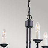 The Chartwell 3 Light Chandelier - Black, featuring a vintage aesthetic with three candle-shaped bulbs elegantly lit and suspended by a chain against a plain light gray background, adds timeless charm to your home décor.